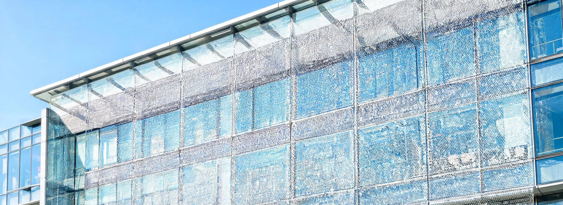 Microperforated solar screen membrane installed on a glazed commercial facade